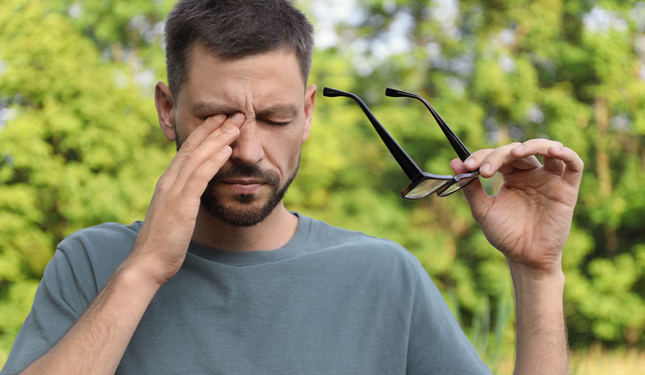 Hombre con gafas rascándose los ojos a causa de la alergia otoñal